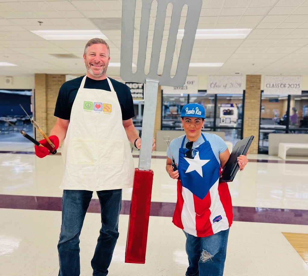 2 teachers in grilling aprons with a giant spatchula